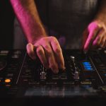 A closeup of a male DJ working under the lights against a dark background in a studio